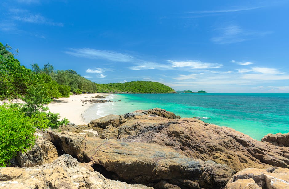 A serene tropical beach with turquoise waters and lush greenery under a vivid blue sky.