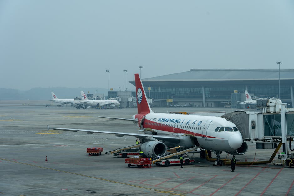 Sichuan Airlines Airbus A320 parked at a busy airport terminal under a cloudy sky.